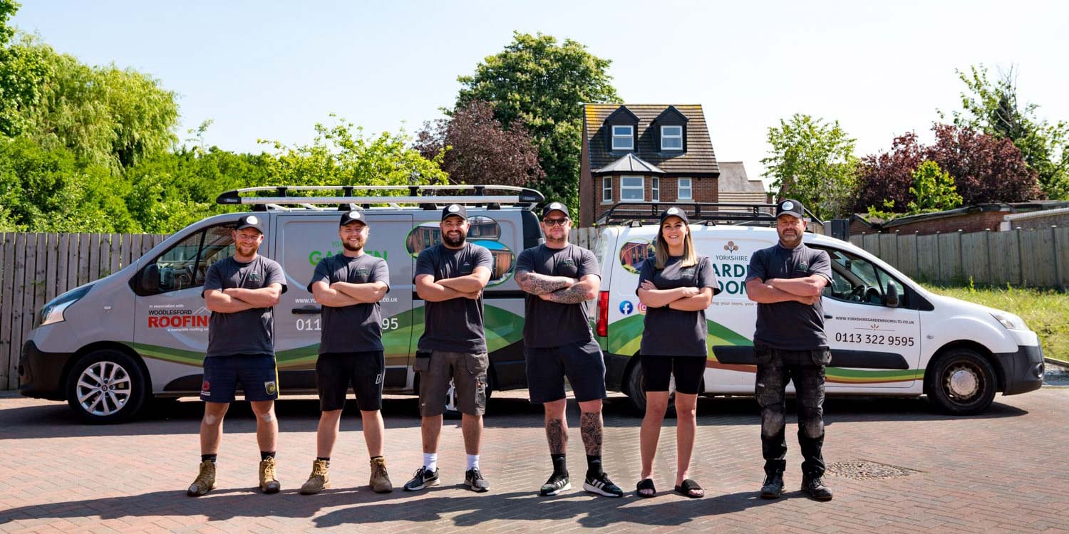 The yorkshire garden room team stood in front of work vans